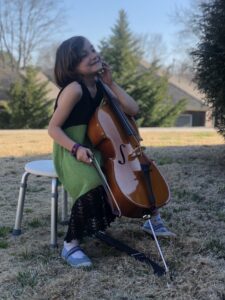 Child playing cello outside